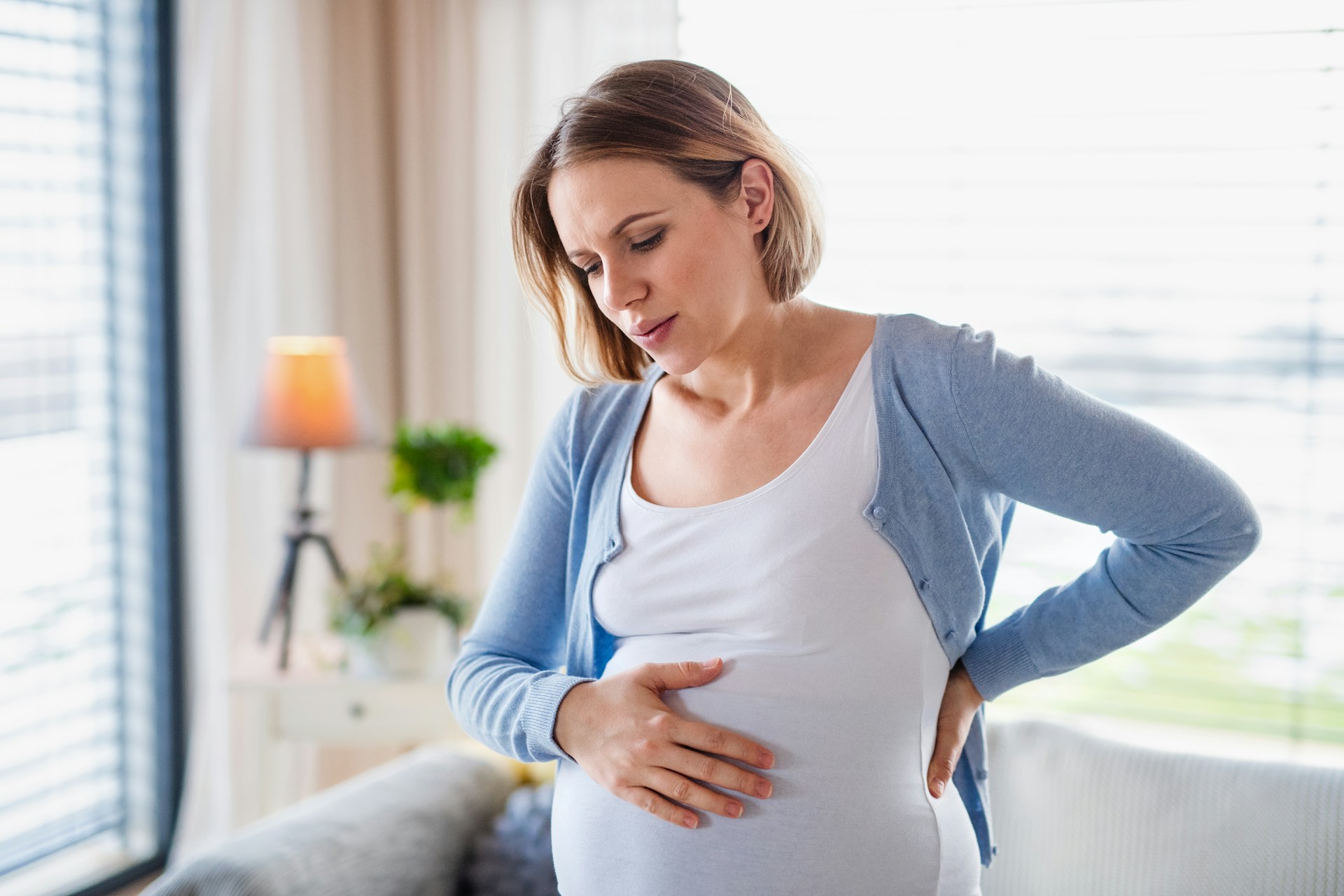 Frau die sorgenvoll ihren Babybauch hält
