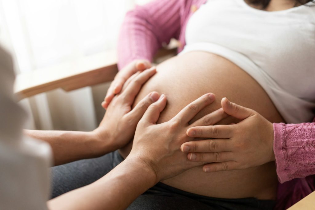 Zwei Hände die auf einem Babybauch liegen